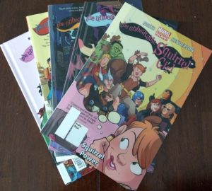 Five comic books laid out on a wooden table (Unbeatable Squirrel Girl, topped by Volume 1, Squirrel Power)
