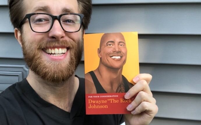 Tres Dean holding up his book, which features The Rocks smiling face
