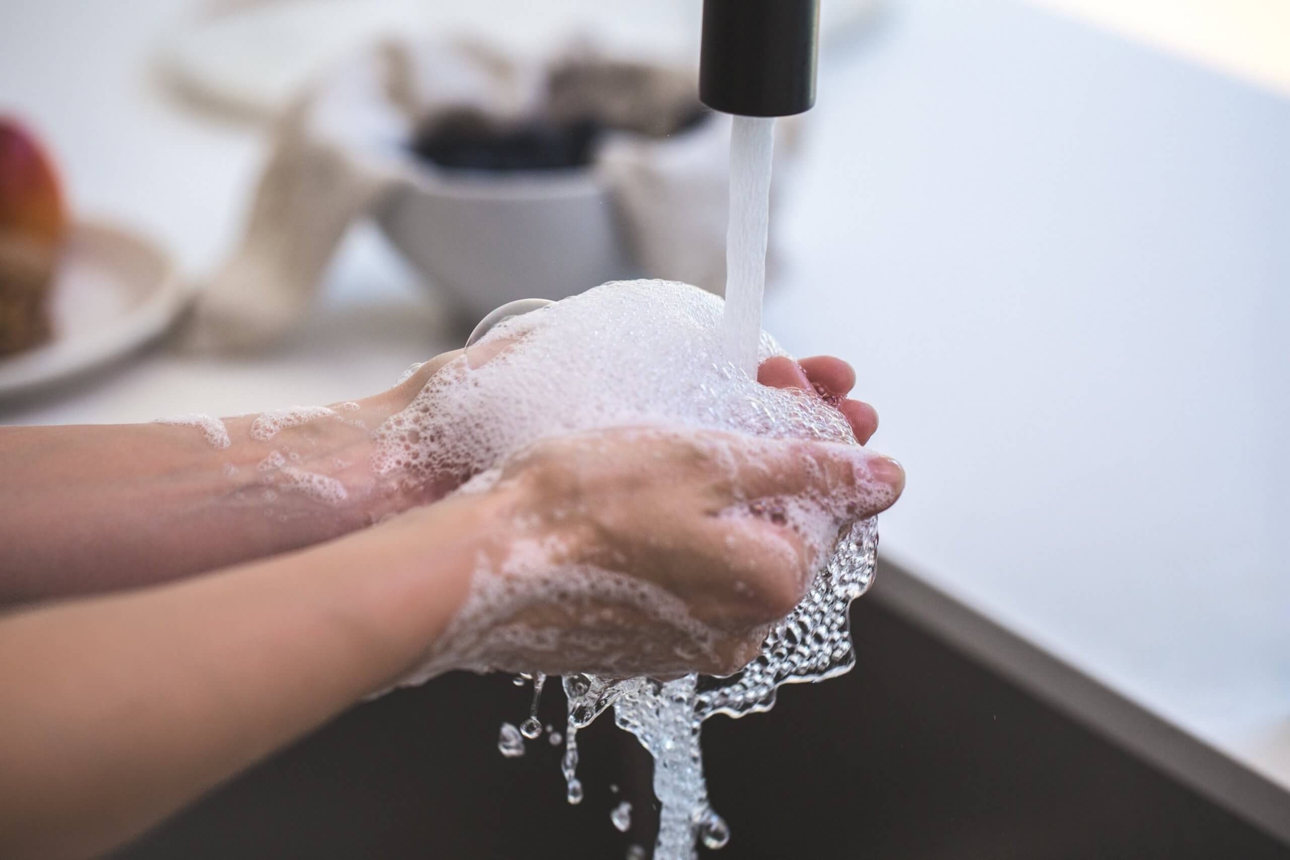 Hands being washed with soap under a running tap