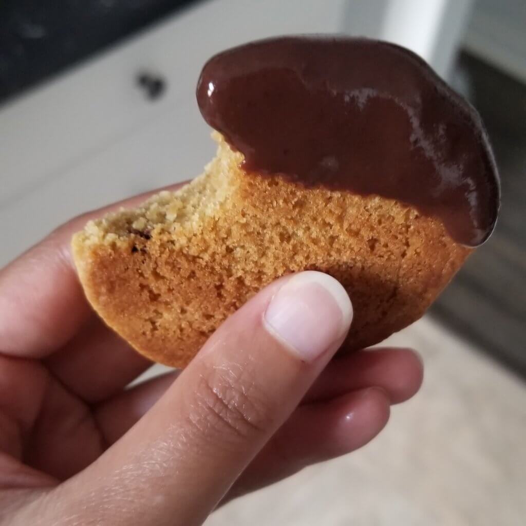 A hand holding a cookie dipped in chocolate