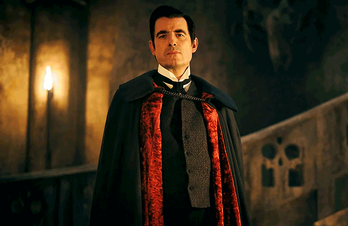 Still from episode 1 of the 2020 BBC/Netflix series Dracula, showing Claes Bang as Dracula, standing in his castle wearing a cloak.
