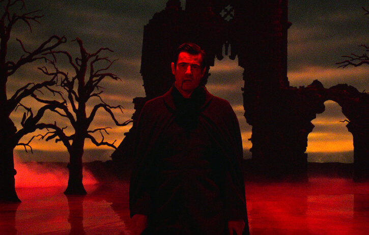 Still from episode 3 of the 2020 BBC/Netflix series Dracula, showing Claes Bang as Dracula against a Gothic backdrop of red mist, dark ruins and ruined masonry