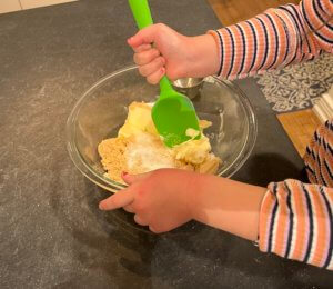 the reviewer's kid's hands stirring some cookie batter ingredients