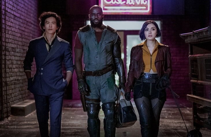 Spike Spiegel, Jet Black, and Faye Valentine walk toward the viewer, a neon sign behind them. They look like they're in an alleyway.