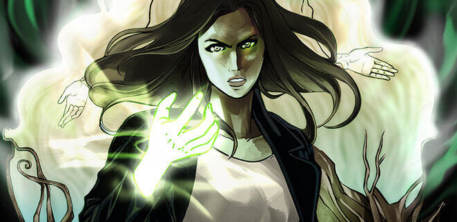 Cover for Carmina #1. A young woman with long, dark hair, stands and looks intently towards the viewer. She has raised one of her arms, which evokes a green glow. Behind her hovers the ghostly image of woman with her hands raised along her sides. Both figures float above a wide shot of a couple of homes with a pickup truck parked near by.