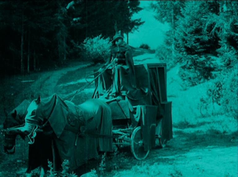 Still from the film Nosferatu showing an eerie scene of a carriage in a forest.