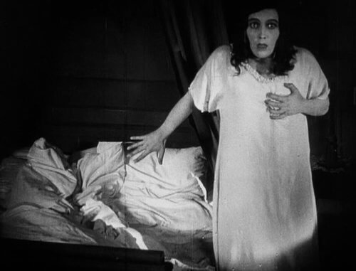 Still from the 1922 film Nosferatu. Greta Schröder in a white dressing gown, looking scared.