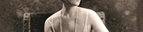 In a vintage photograph, a short-haired white woman wears a loose white dress that resembles a flapper's costume and looks to the right