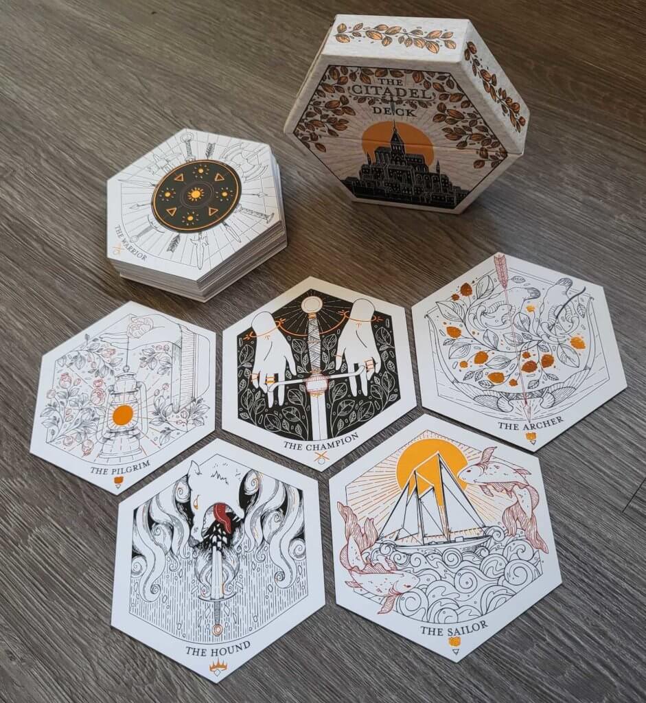 The hexagonal box for the Citadel deck, along with a selection of cards from it: the Pilgrim, the Champion, the Archer, the Hunter, the Sailor