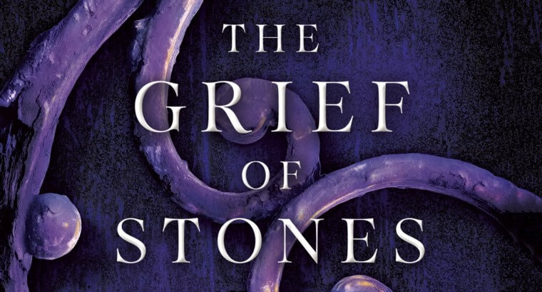 swirling stone or metalwork with one glowing amber oval provides the backdrop to the title and author on the cover of the Grief of Stones by Katherine Addison.