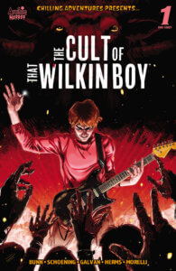 Redheaded white teen bingo wilkin stands before a group of waving, black hands and arms, a guitar strapped around his shoulders. He's backlit by red and the entire scene is menacing.