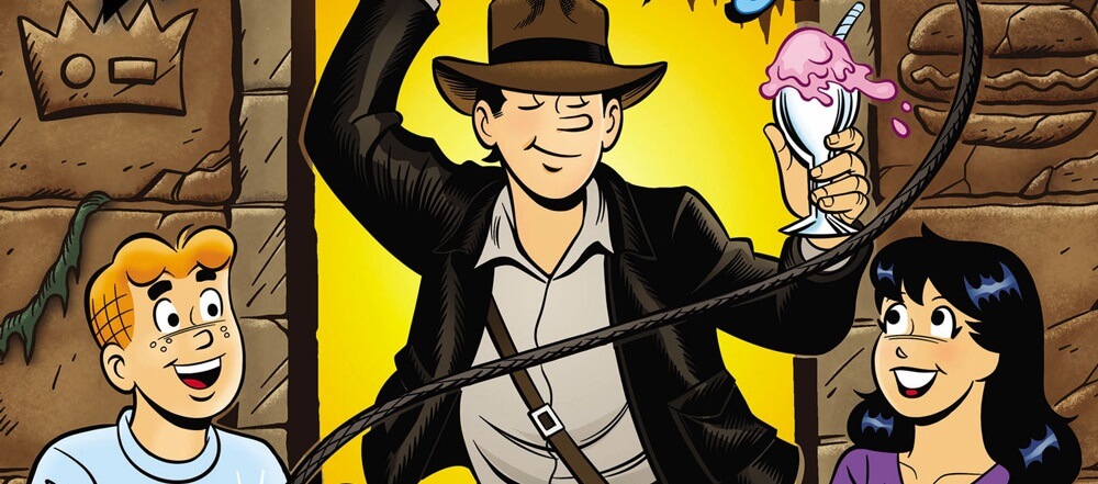White teenager Jughead Jones wears an outfit that resembles Indiana Jones. His friends are posed around him as he stands framed in an archway which resembles one from the Raiders poster. He weilds a bullwhip, which is tied around the hero sandwich Reggie Mantle had been set to take a bite ot of; in his free hand is a cone of ice cream.