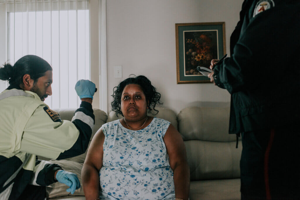 Photo from film's recreations, first responder tends to Cindy as she is questioned by a detective