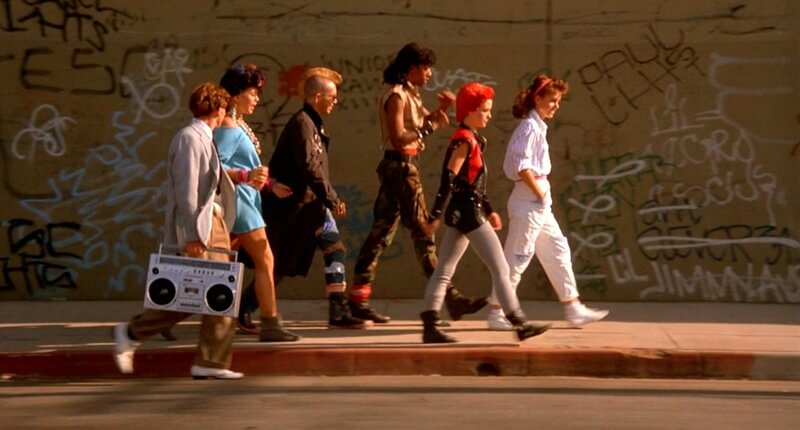 Still from the film The Return of the Living Dead showing a group of punks walking in front of graffiti.