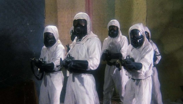 Still from the film Zombi 3 showing a group of armed men with gas-marks and protective gear.