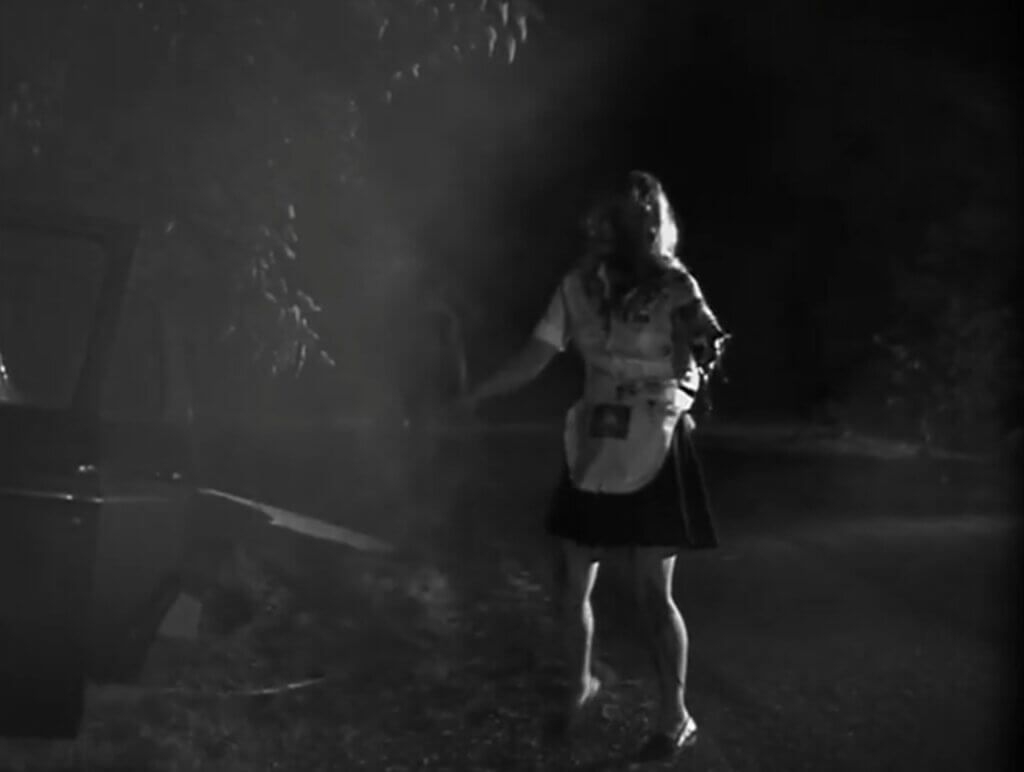 Still from one of the newly-filmed scenes for the Night of the Living Dead 30th Anniversary Edition. A one-armed zombie in a waitress' uniform shambles through scrubland.