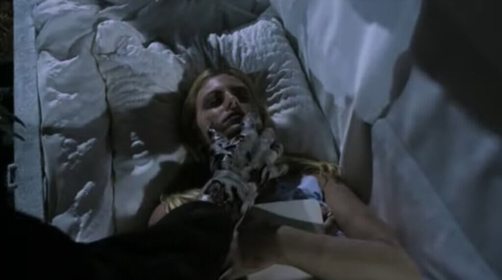 Still from the film Children of the Living Dead. Shows a zombie hand reaching put tp a body in a coffin.