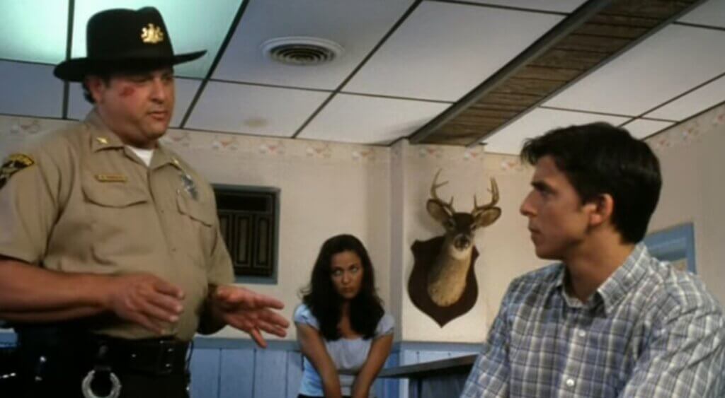 Still from the film Children of the Living Dead. Shows the sheriff and the male and female leads talking in a diner.