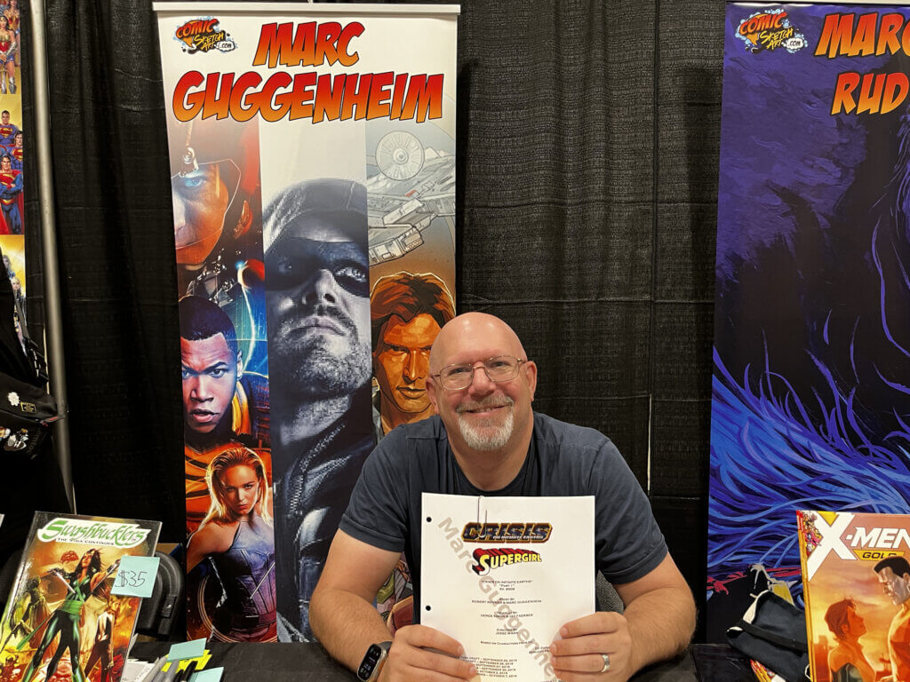 Marc Guggenheim holds up the script of the Supergirl episode of 'Crisis on Infinite Earths' at Fan Expo Canada 2024