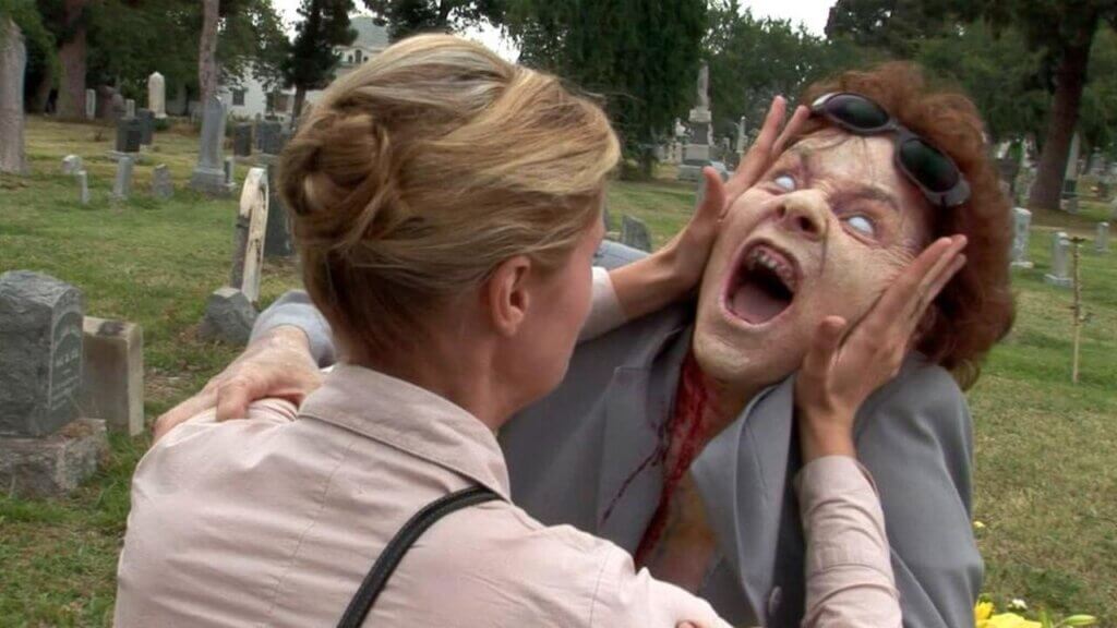 Still from the film Night of the Living Dead 3D. A woman grapples with a zombie in a cemetery.