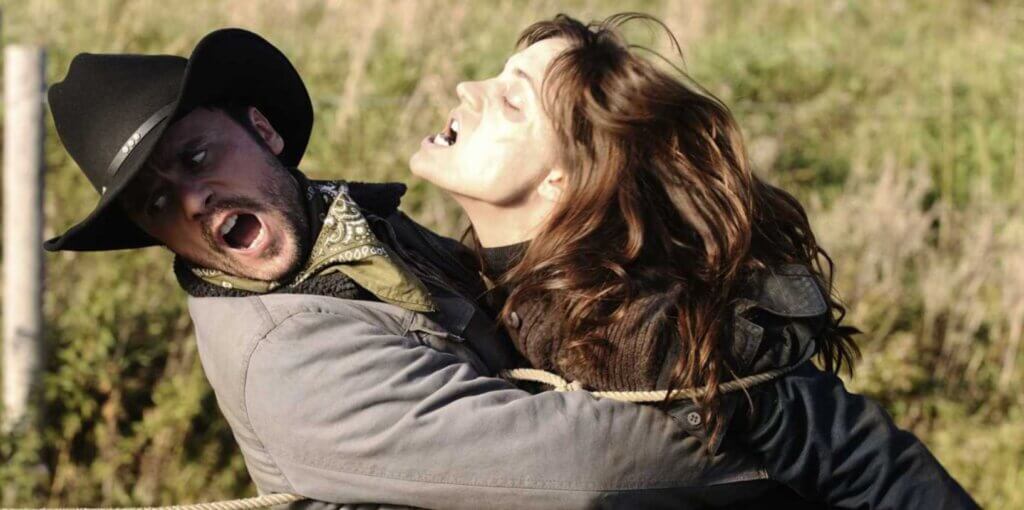 Still from the film Survival of the Dead. A young girl, zombified, attacks a man in a cowboy hat.